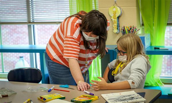 Teacher helps student with food model